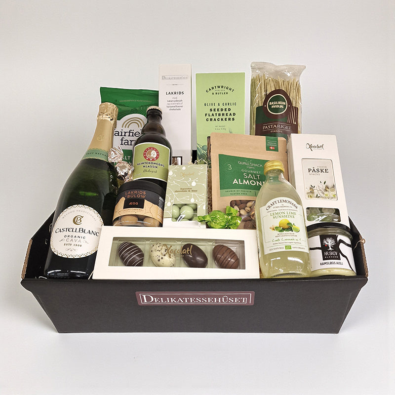 Flot påskegavekurv fra Delikatessehuset med mousserende vin, chokoladepåskeæg, lakrids og diverse påskedelikatesser.