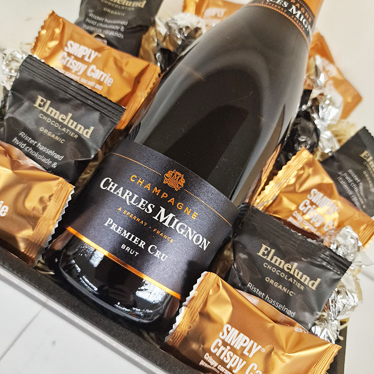 Tæt billede af Charles Mignon champagne flaske i gavekurv omgivet af Simply og Elmelund chokolade.
