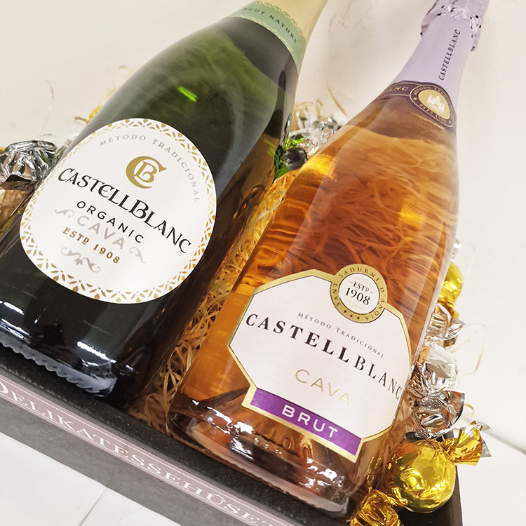 Nærbillede af gavekurv med to flasker Castellblanc Cava og indpakkede chokoladekugler fra Delikatessehuset.