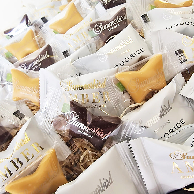 Tætpå af enkeltindpakkede Summerbird Organic chokolader i en eksklusiv gavekurv fra Delikatessehuset.