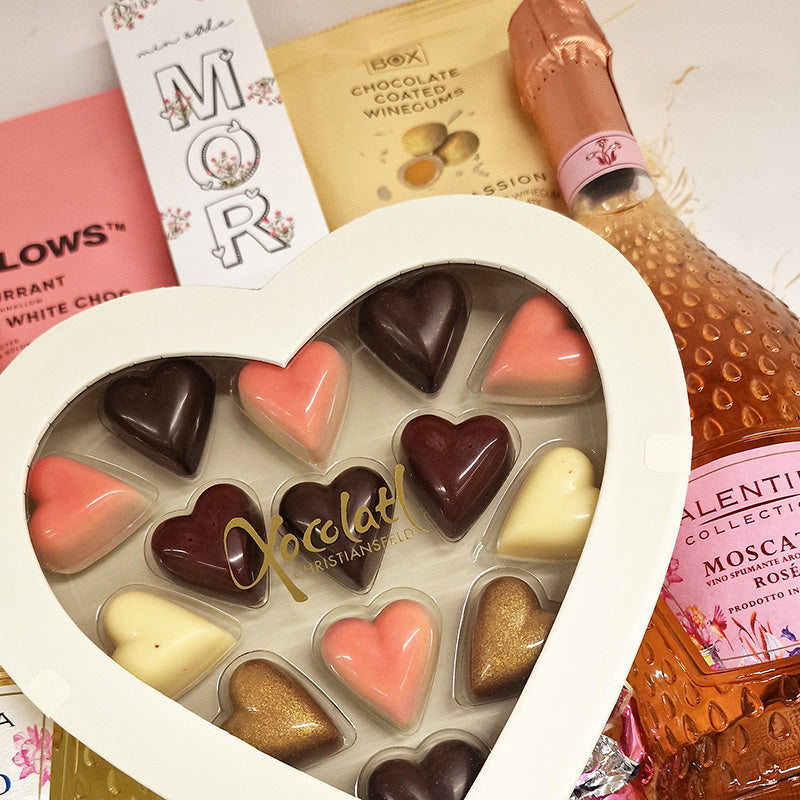 Stor og flot gavekurv med to søde flasker bobler, skumfiduser og et stort chokoladehjerte med fyldte chokoladehjerter i til morsdag