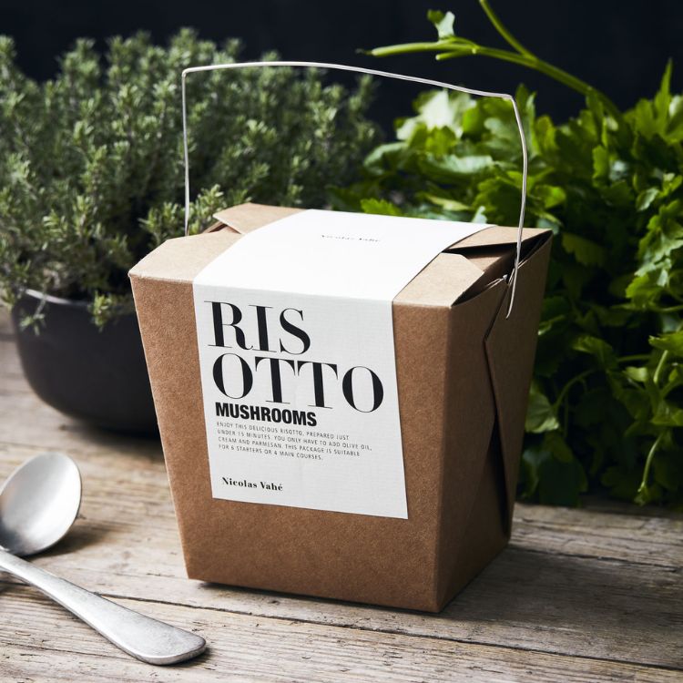 Nicolas Vahé risotto med svampe i en rustik papæske ved siden af friske krydderurter.