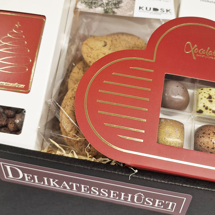 Tæt billede af en julekurv fra Delikatessehuset med fyldte chokolader, småkager og lækre julelækkerier.