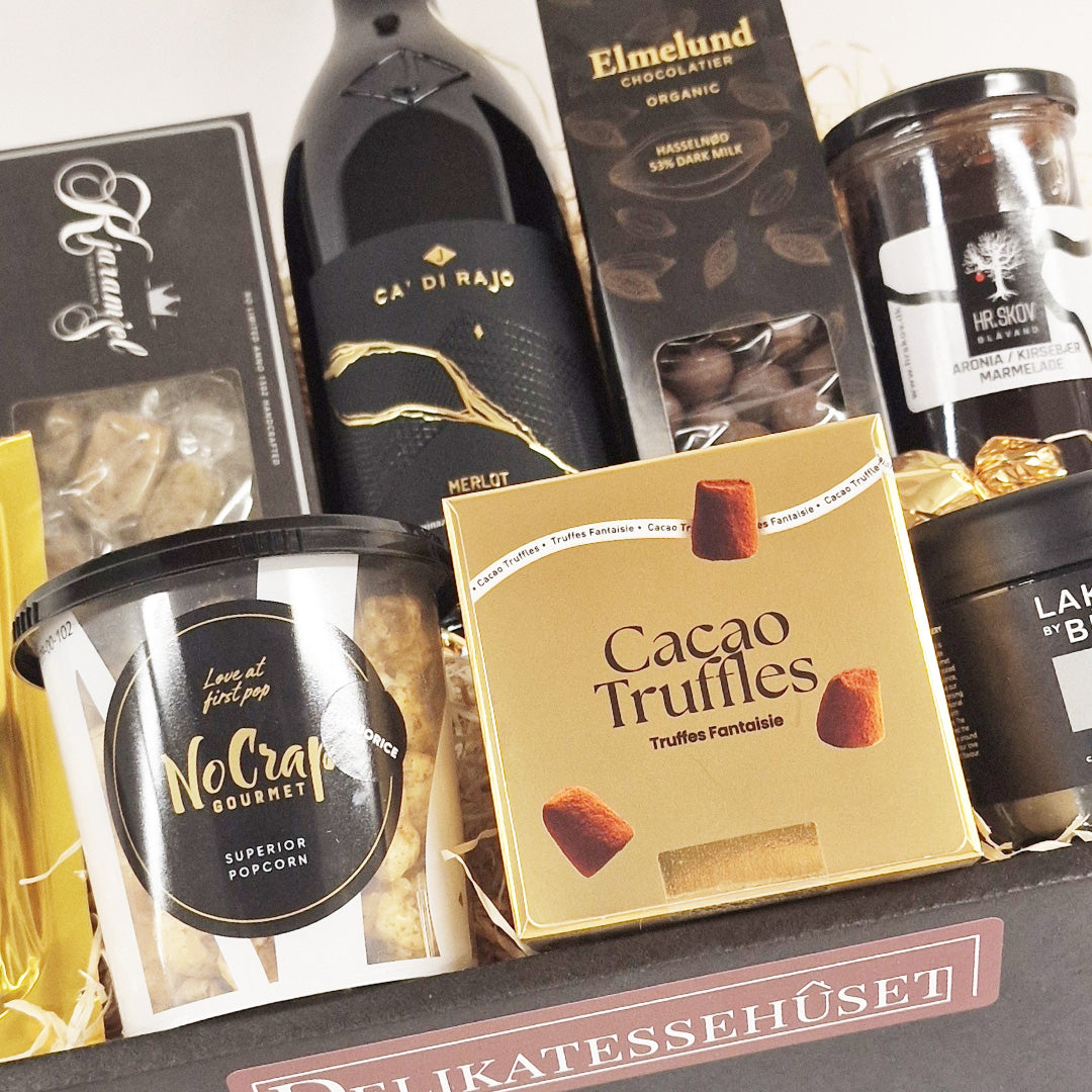 Eksklusiv gavekurv med rødvin, kakaotrøfler, gourmet popcorn og chokolade fra Delikatessehuset.