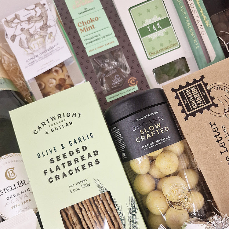 Gavekurv med mintfarvede delikatesser, herunder Cartwright & Butler crackers, Lakrids by Bülow og Tak chokolade.