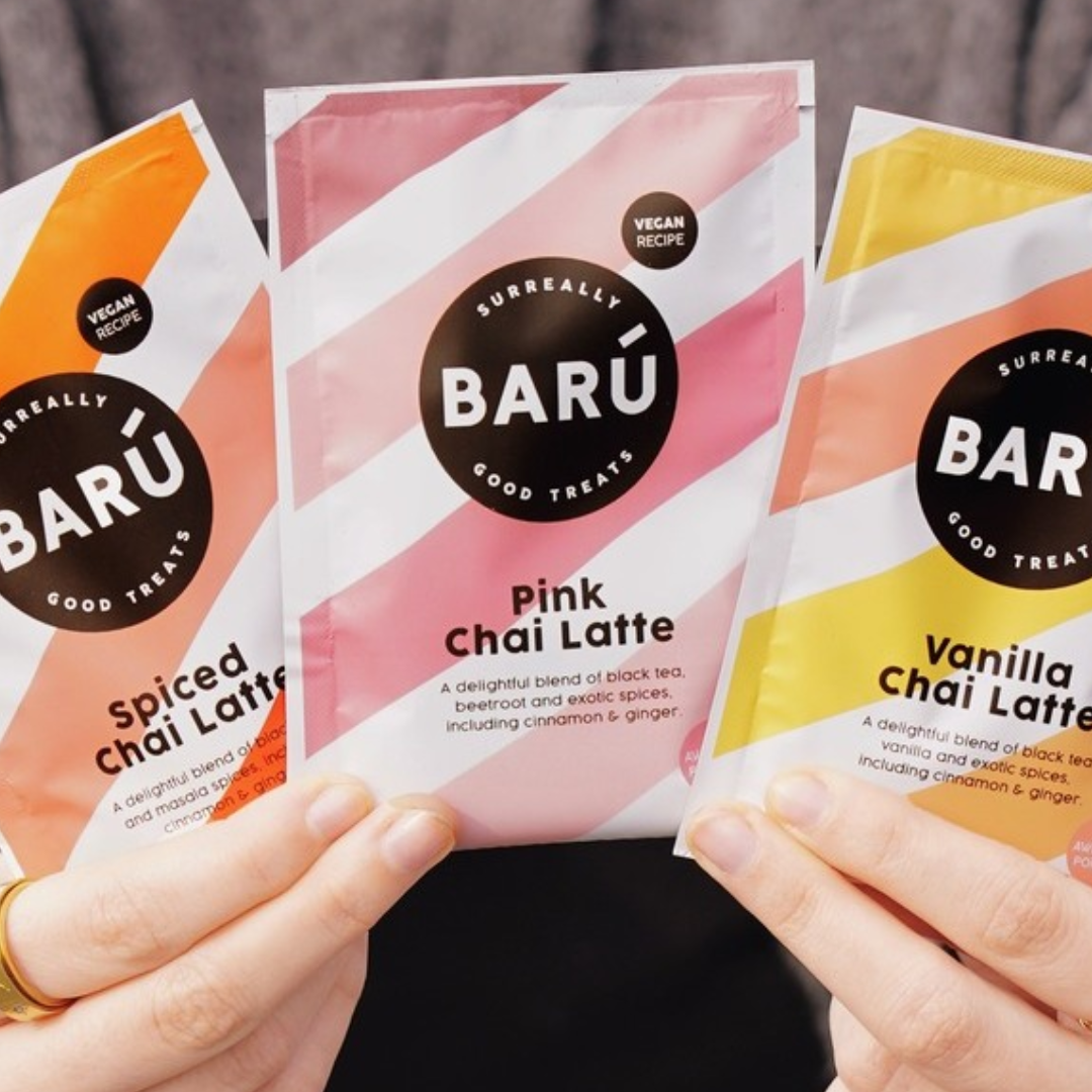 Tre breve med Baru Chai Latte i varianterne Spiced, Pink og Vanilla holdes i hænderne.