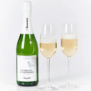 Flaske med Sparkling Summerbird te og to fyldte glas med bobler på hvid baggrund.